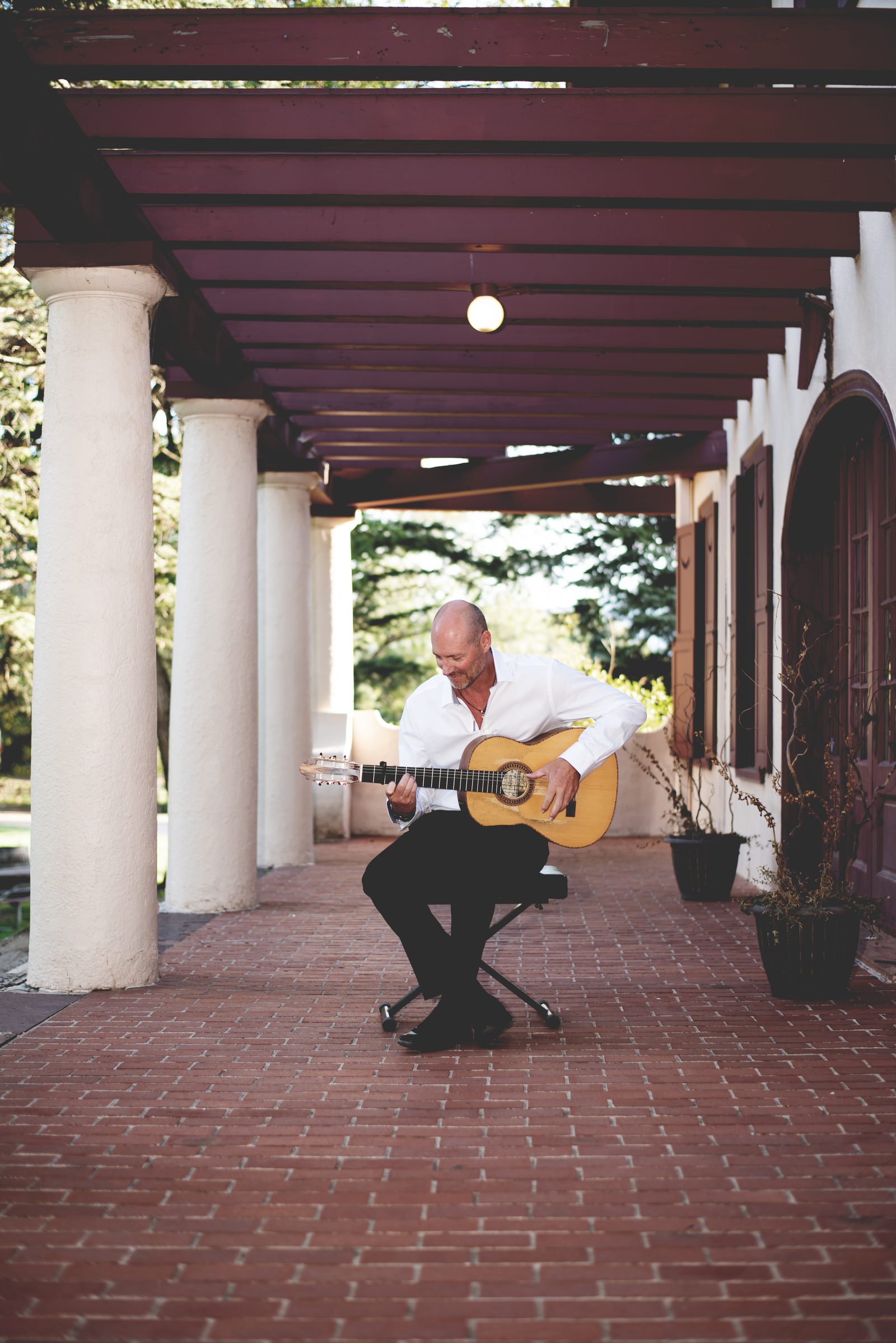 Gary Meyers playing flamenco guitar under a colonnade.