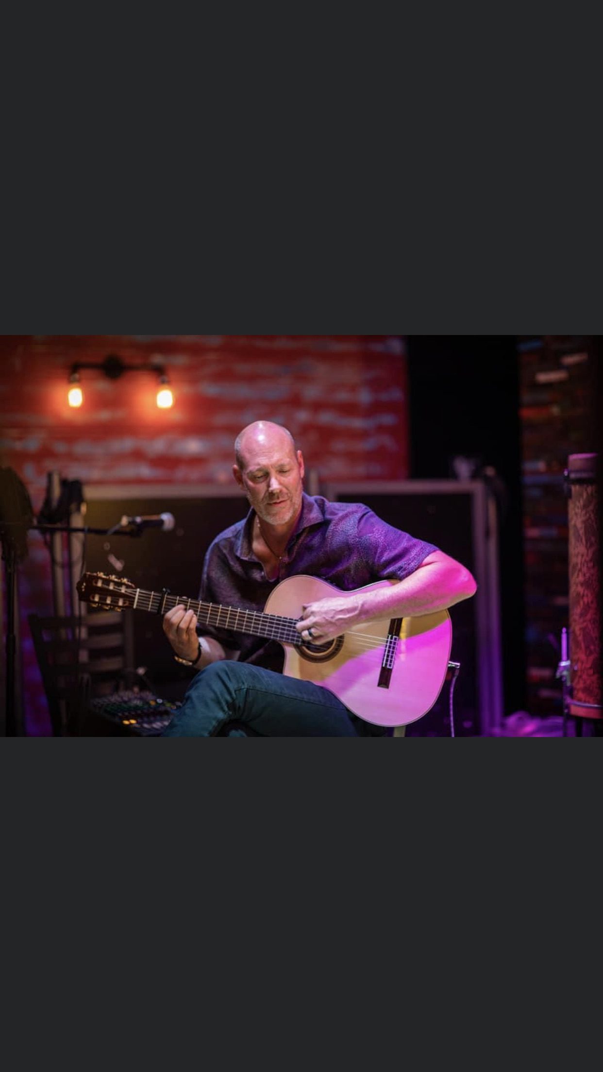 Gary Meyers playing a seated set on a venue stage.