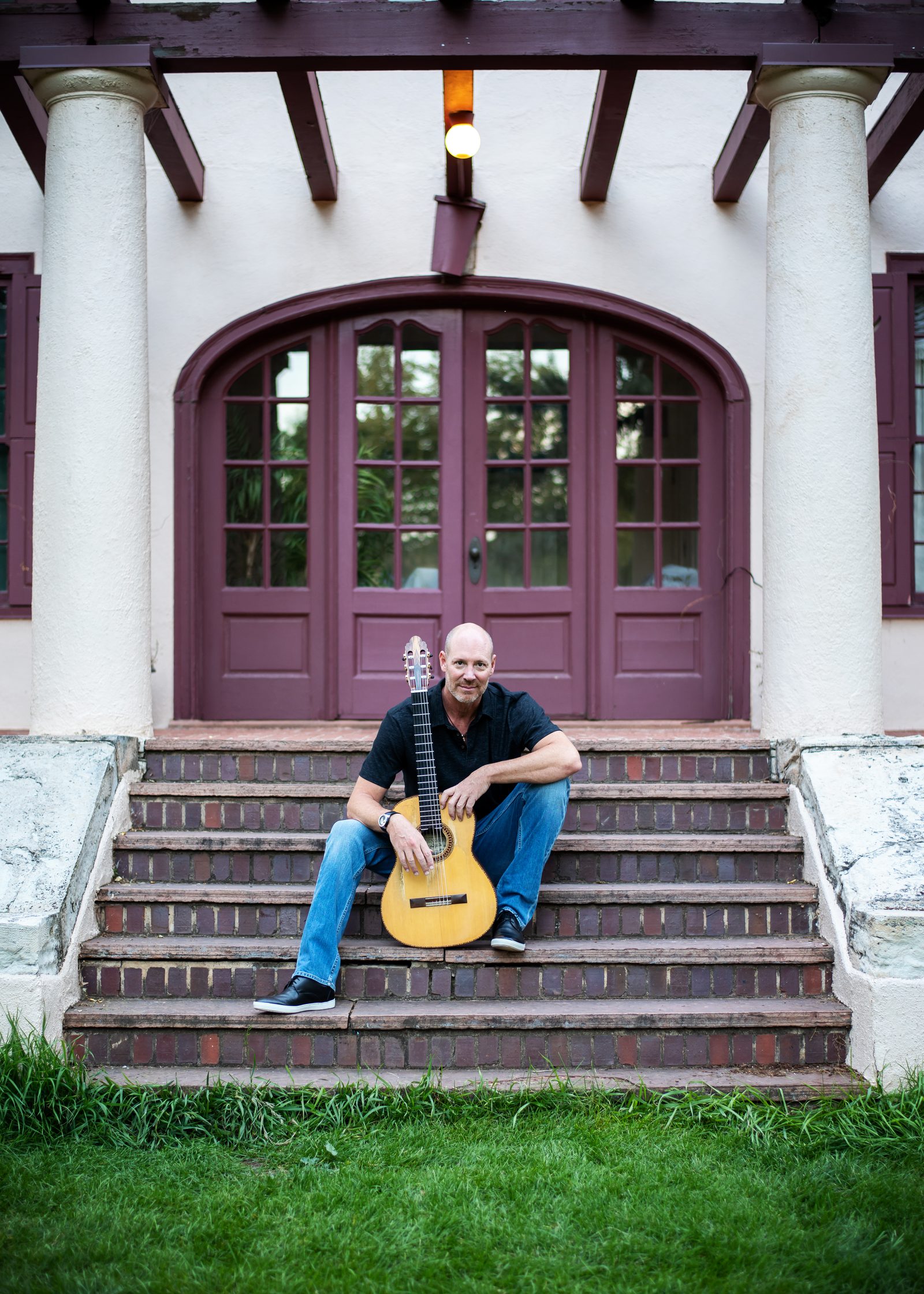 Gary Meyers seated on brick steps with his flamenco guitar.