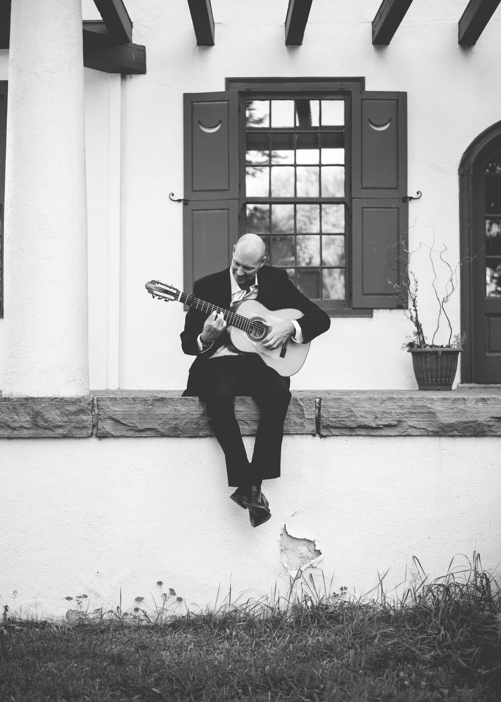 Gary Meyers playing beneath a shuttered window, black and white.