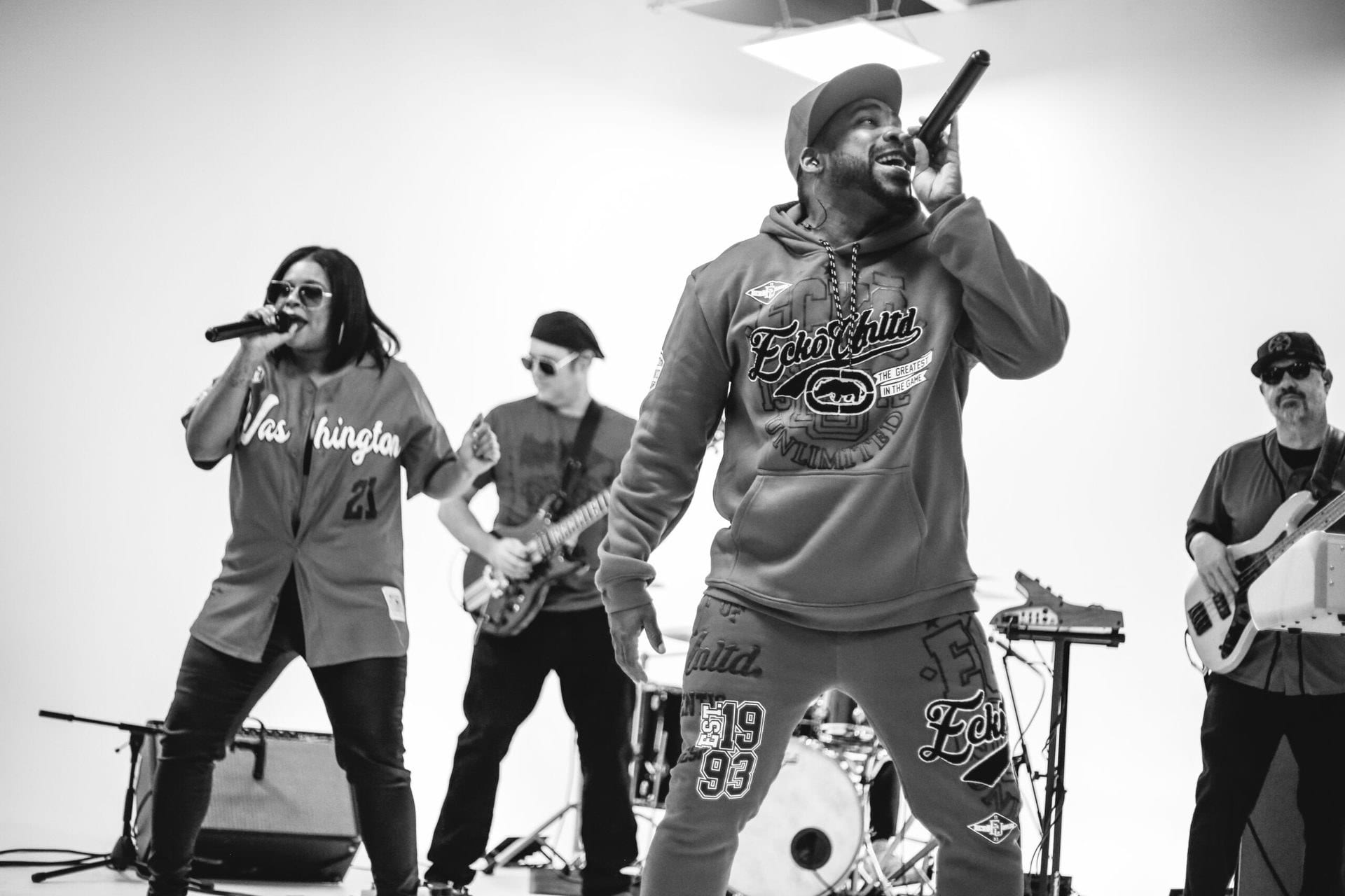 Two singers out front with guitar and keys behind them, in black and white.