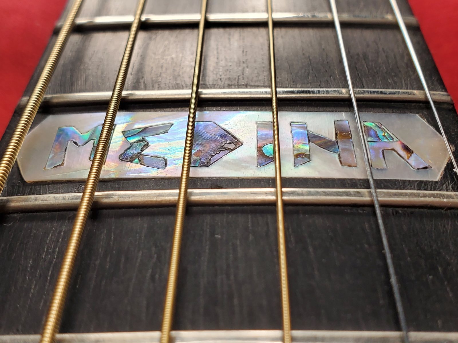 His surname inlaid in abalone along a guitar fretboard.
