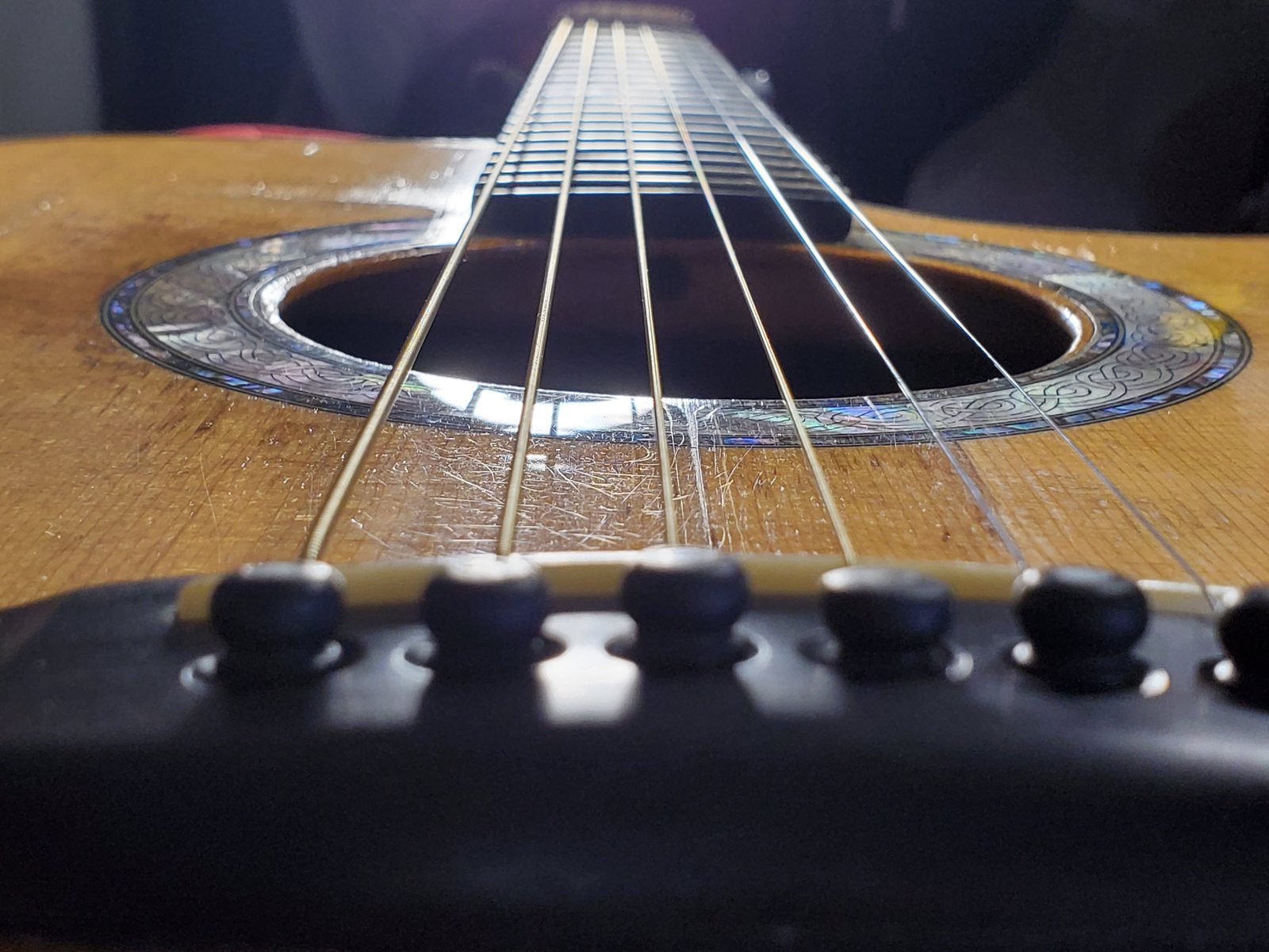 The soundhole and strings of his acoustic guitar, close up.
