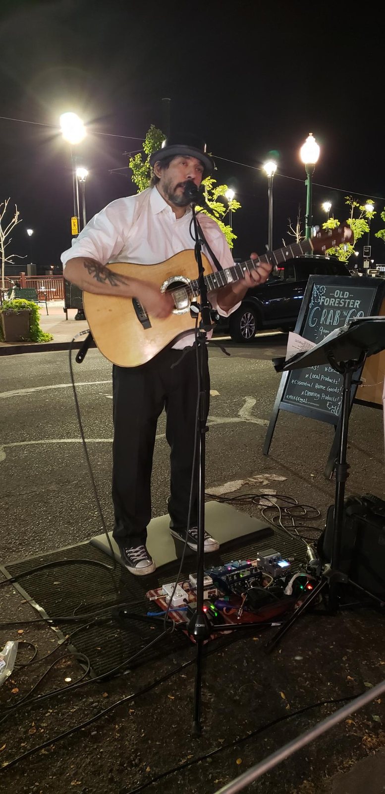 Tony Medina playing an outdoor set at night beside a streetlight.