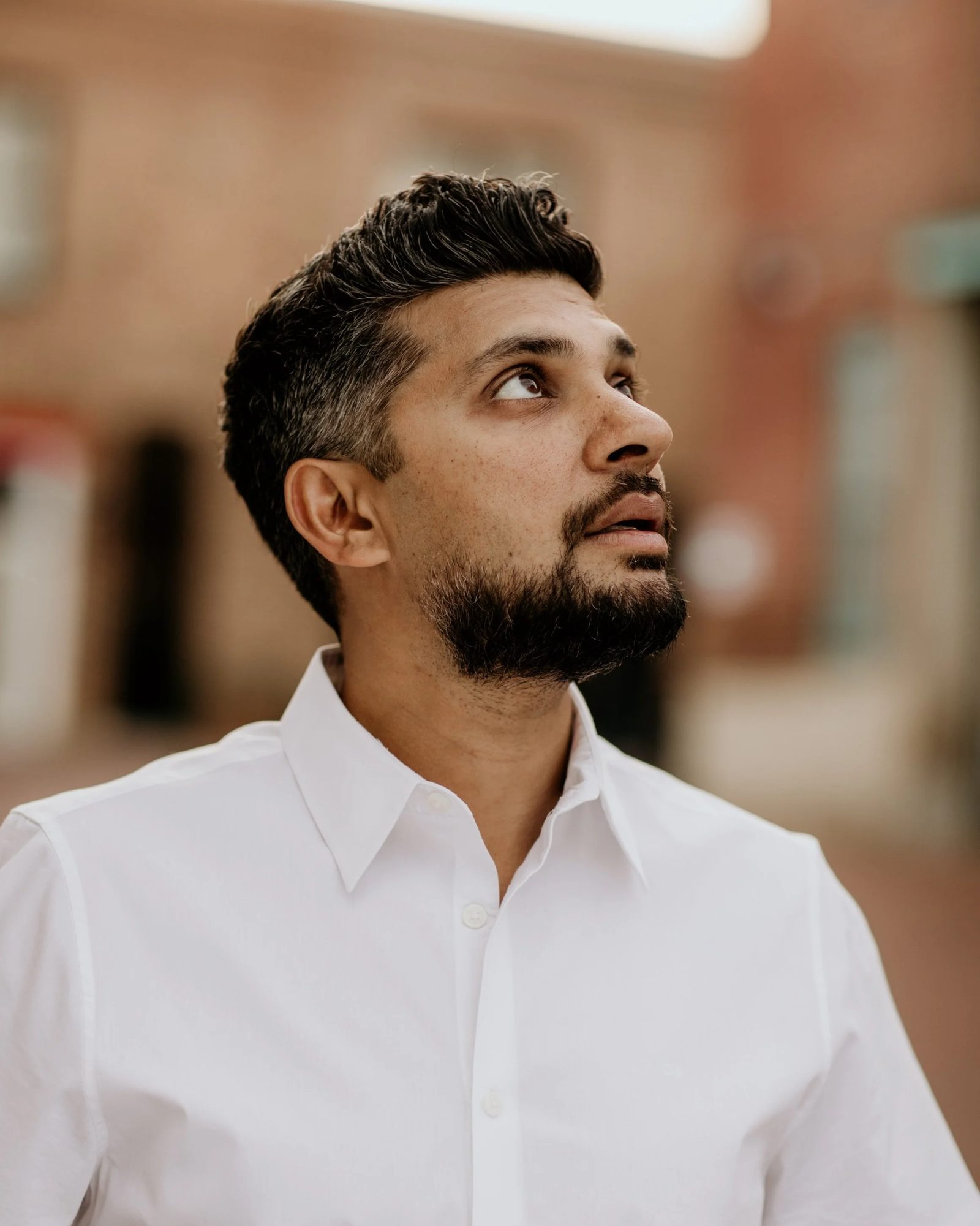 Tejas Singh in a white shirt, looking up past the camera.