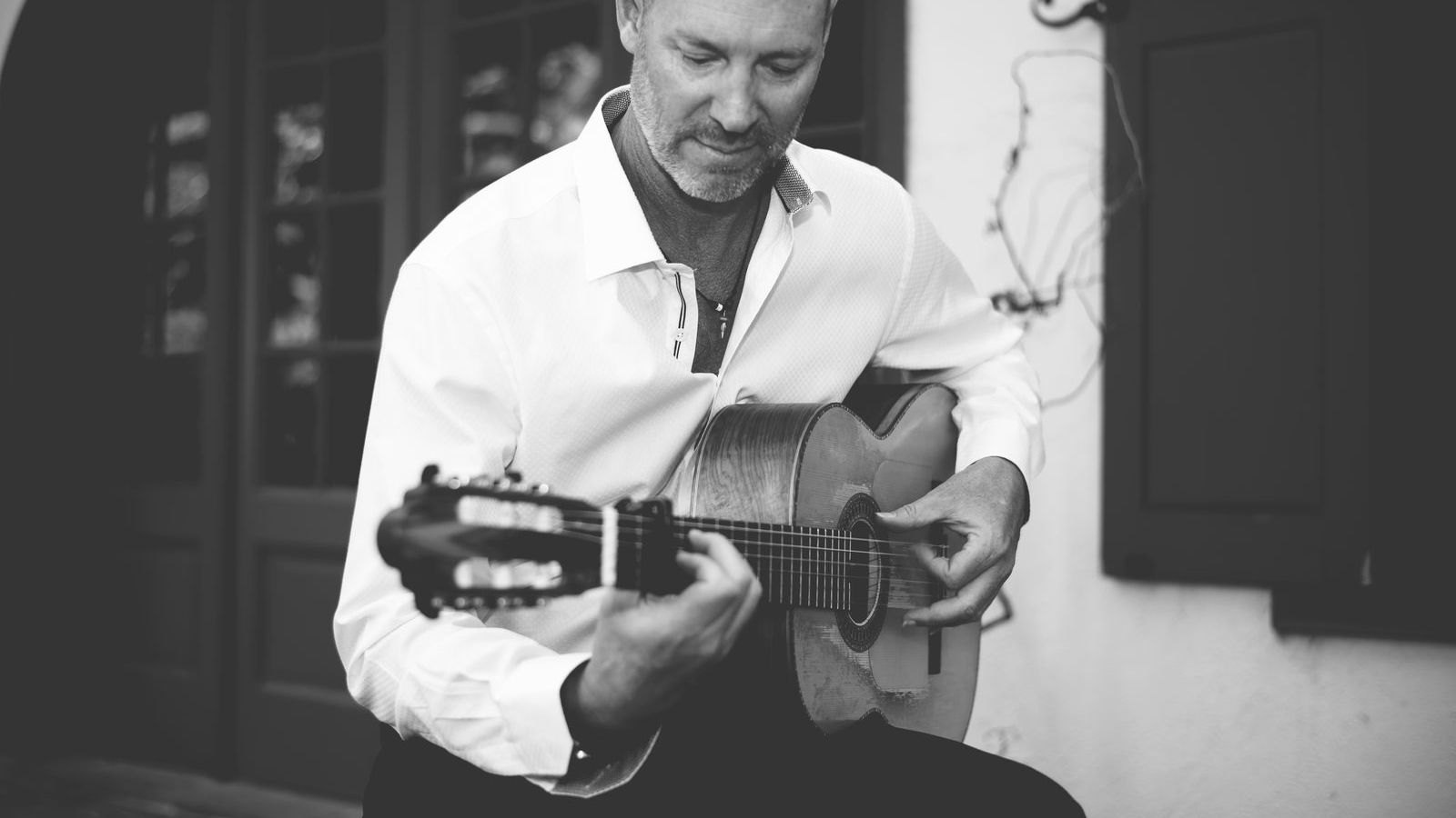 Gary Meyers playing flamenco guitar beside a Spanish doorway, in black and white.